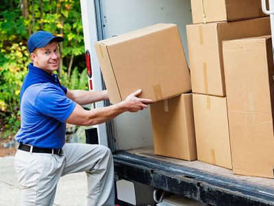 Photo of a delivery man lifting cardboard boxes from the back of his truck.